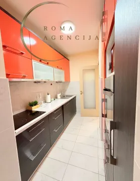 Moderna kuhinja sa narandžastim gornjim elementima i tamnim donjim elementima. - image 5