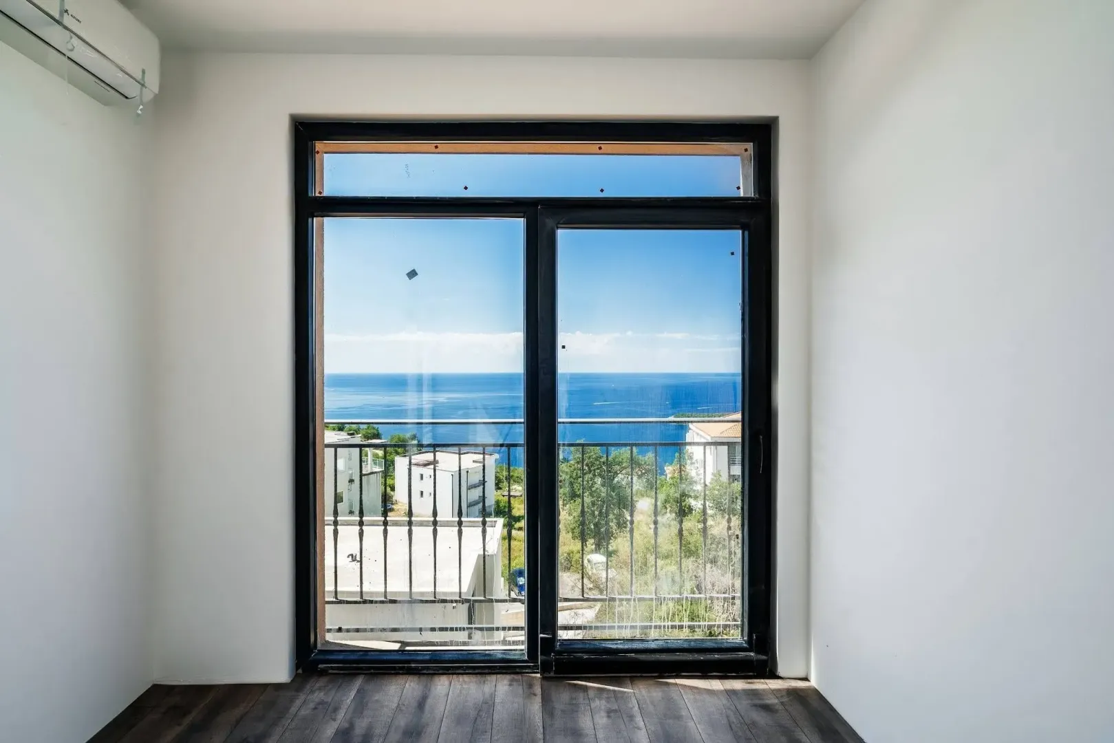 Sea view through a large glass window from an empty room.
