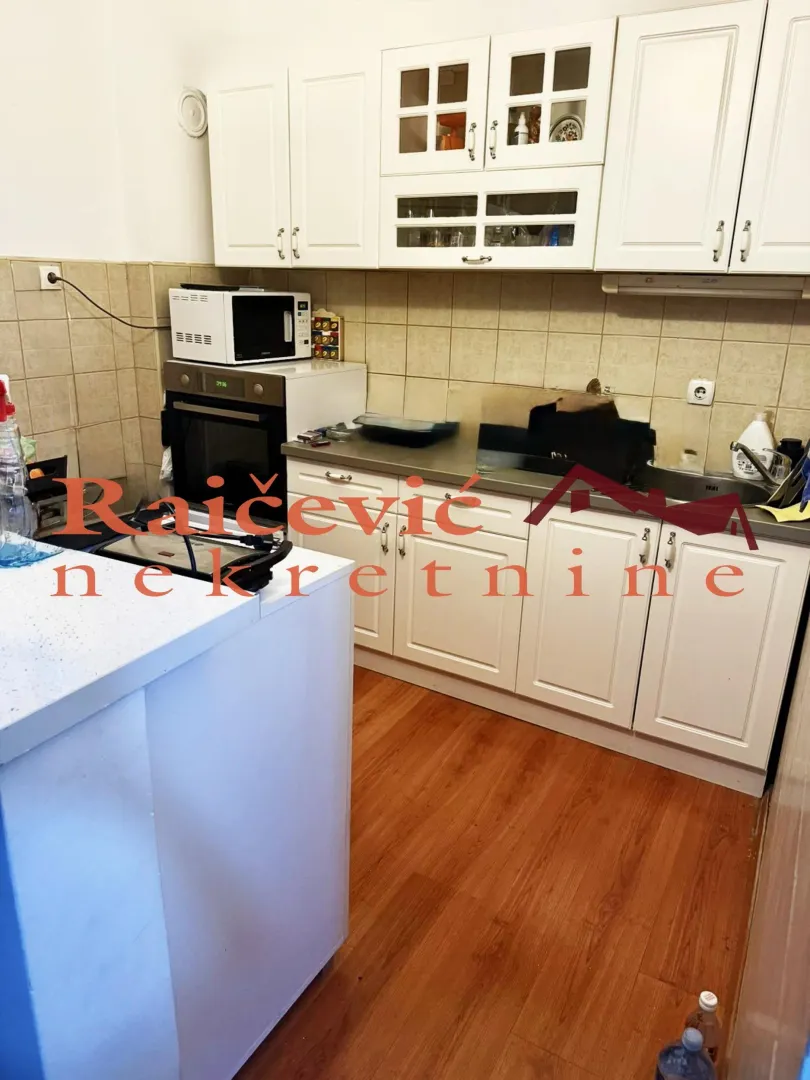 Kitchen with white cabinetry, built-in oven and microwave.