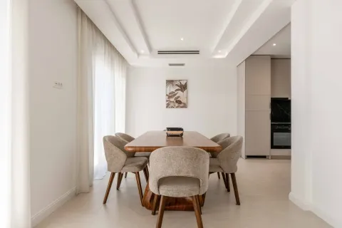 Modern dining area with a wooden table and chairs connected to the kitchen. - image 24