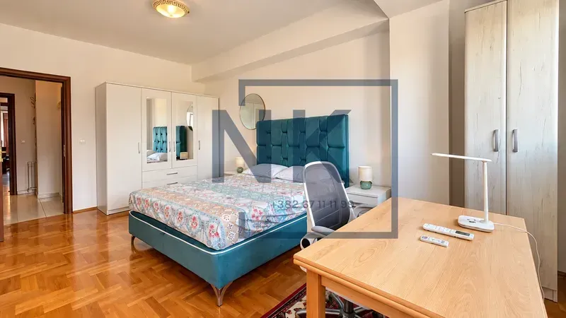 Furnished bedroom with a double bed, wardrobe, and a desk.