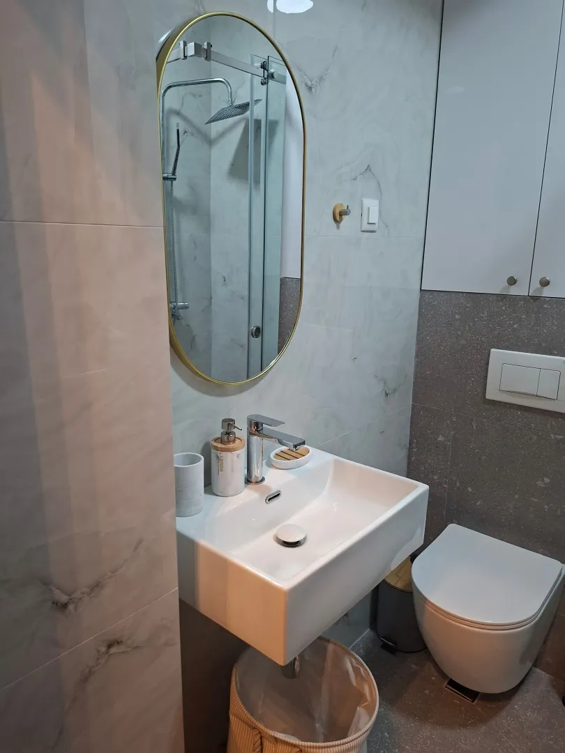 Modernly equipped bathroom with a washbasin, mirror, and toilet.