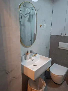 Modernly equipped bathroom with a washbasin, mirror, and toilet. - image 3