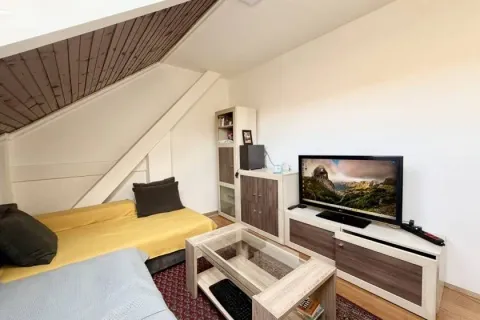 Dnevna soba u potkrovlju sa garniturom i televizorom. - image 10