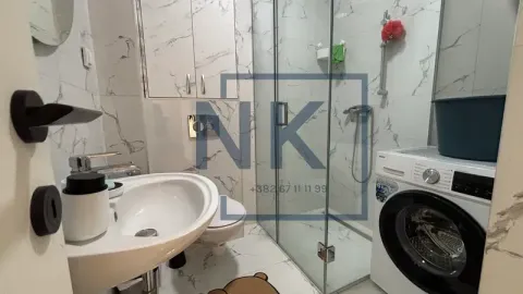 Modern bathroom with a sink, walk-in shower, and washing machine. - image 9
