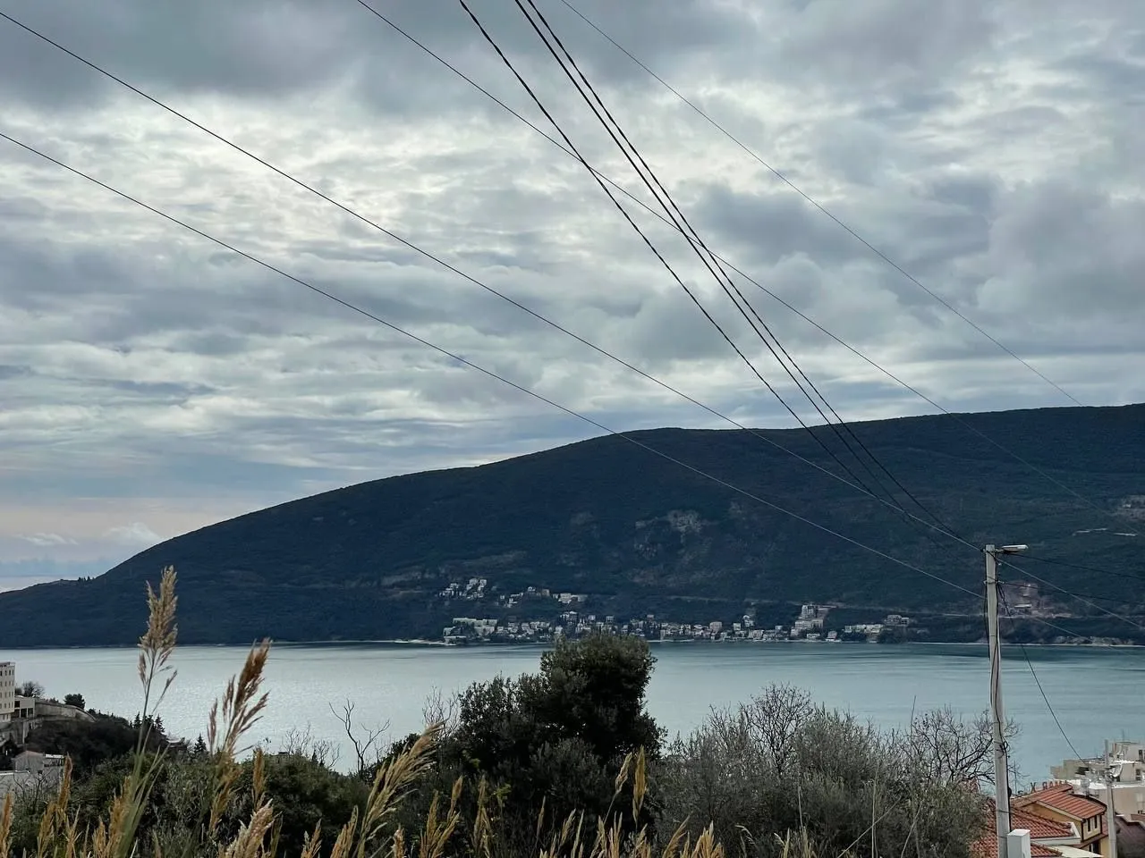 Pogled sa imanja na more i okolna brda pod oblačnim nebom.