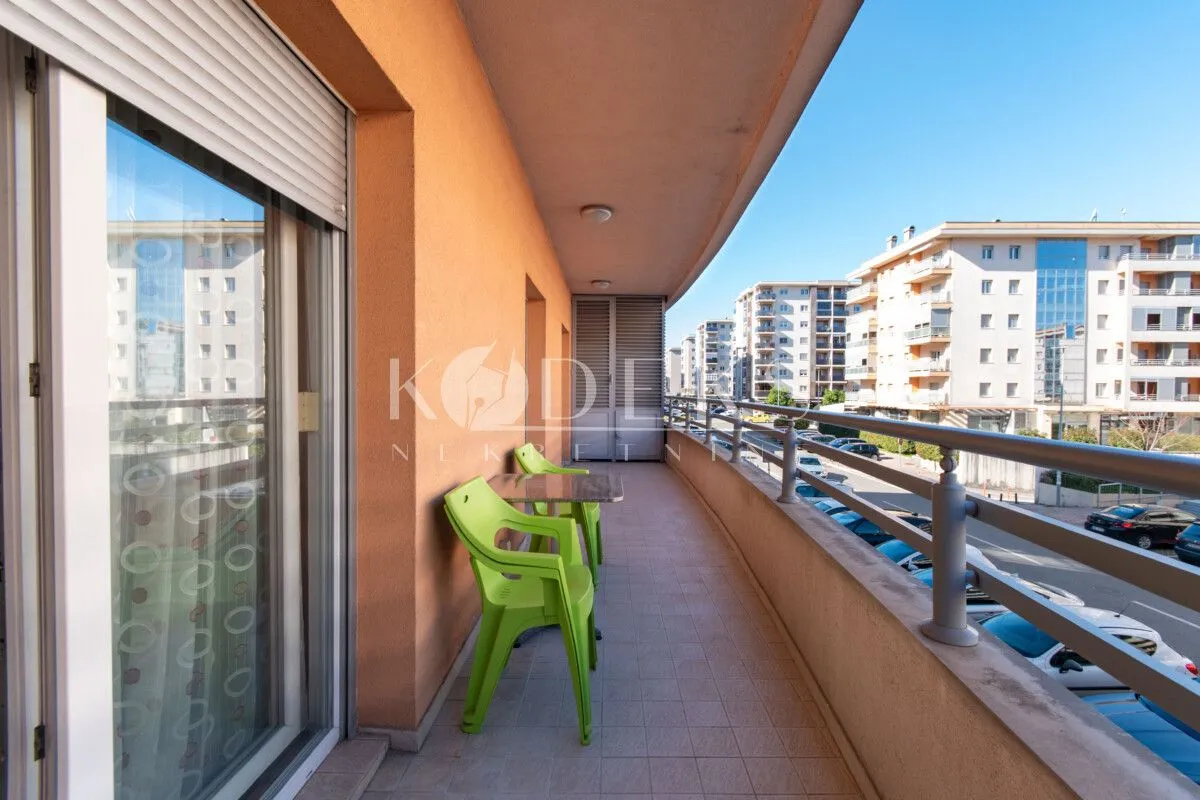 Dugačak natkriveni balkon sa garniturom za sjedenje i pogledom na ulicu.