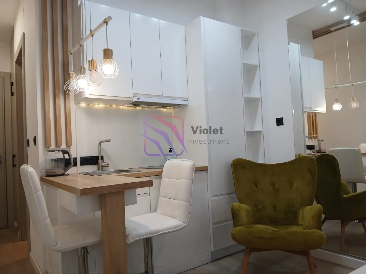 Moderna bijela kuhinja sa šankom i trpezarijskim stolicama.