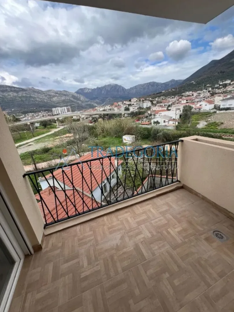 Manji popločani balkon sa pogledom na grad i planine.