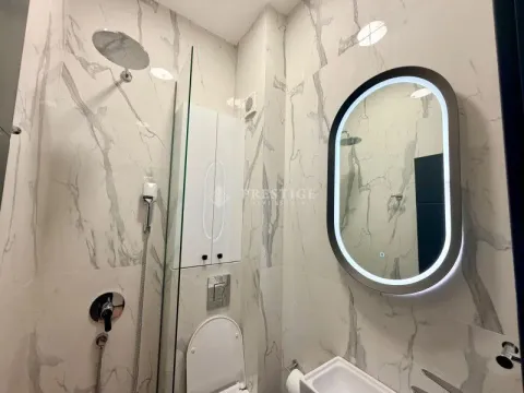Modern bathroom with a shower cabin, white marble tiles, and an illuminated mirror. - image 17