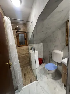 A bathroom featuring a shower cabin, toilet, and tiled walls. - image 7