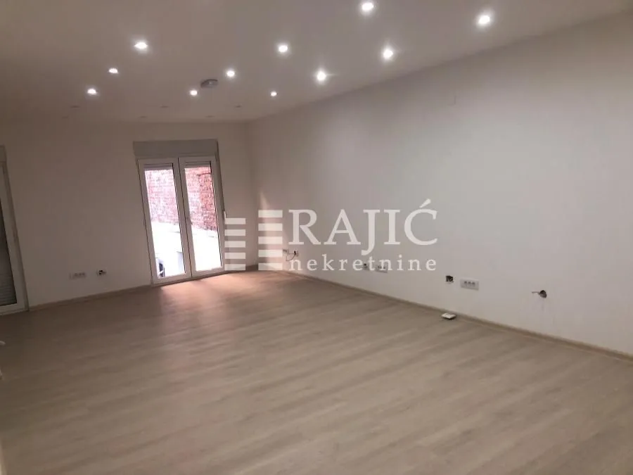 Empty room with laminate flooring and recessed lighting.