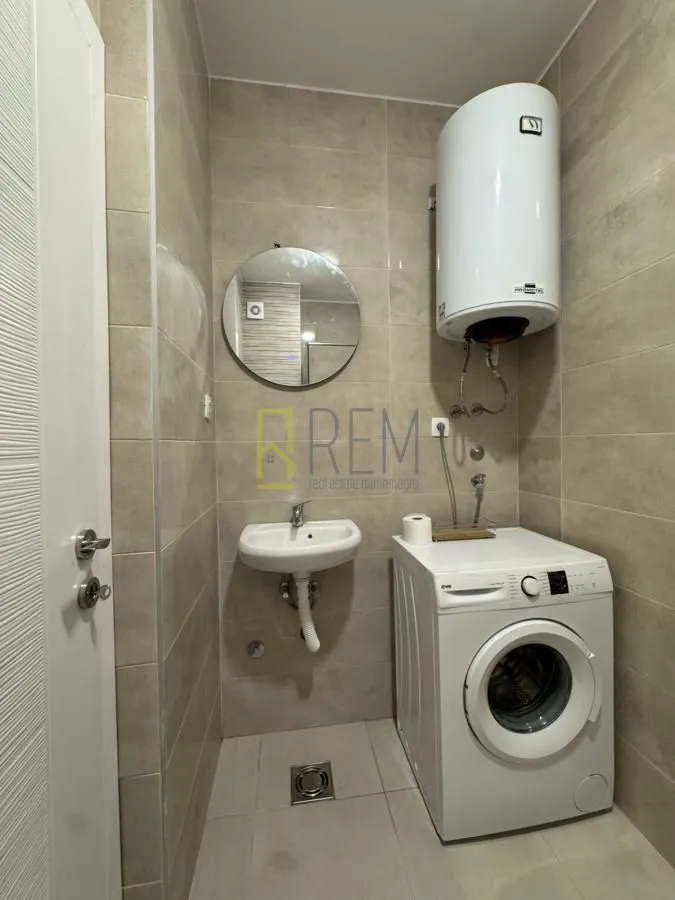 Small bathroom with a shower, sink, and washing machine.