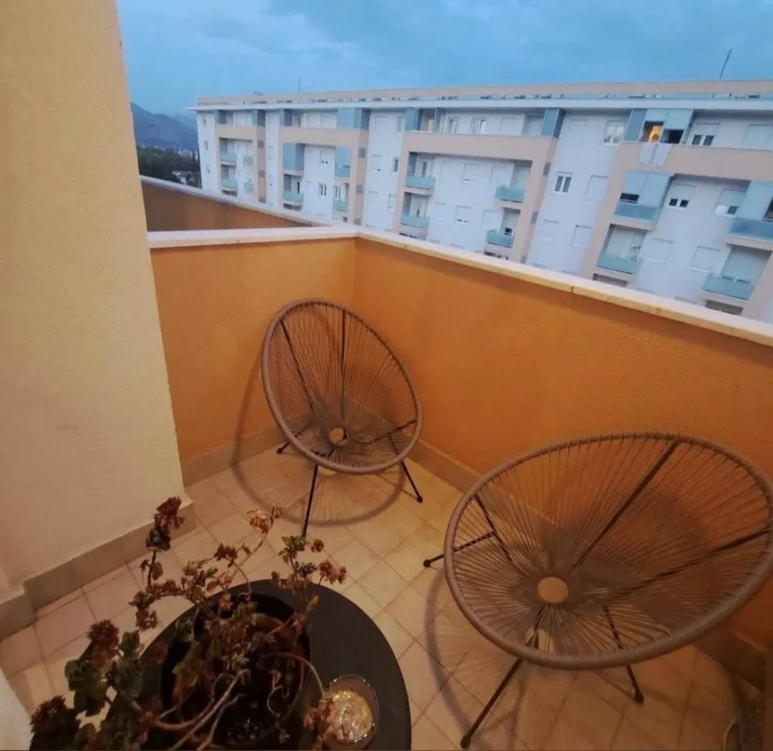 Namješten balkon sa dvije stolice i pogledom na okolne zgrade.