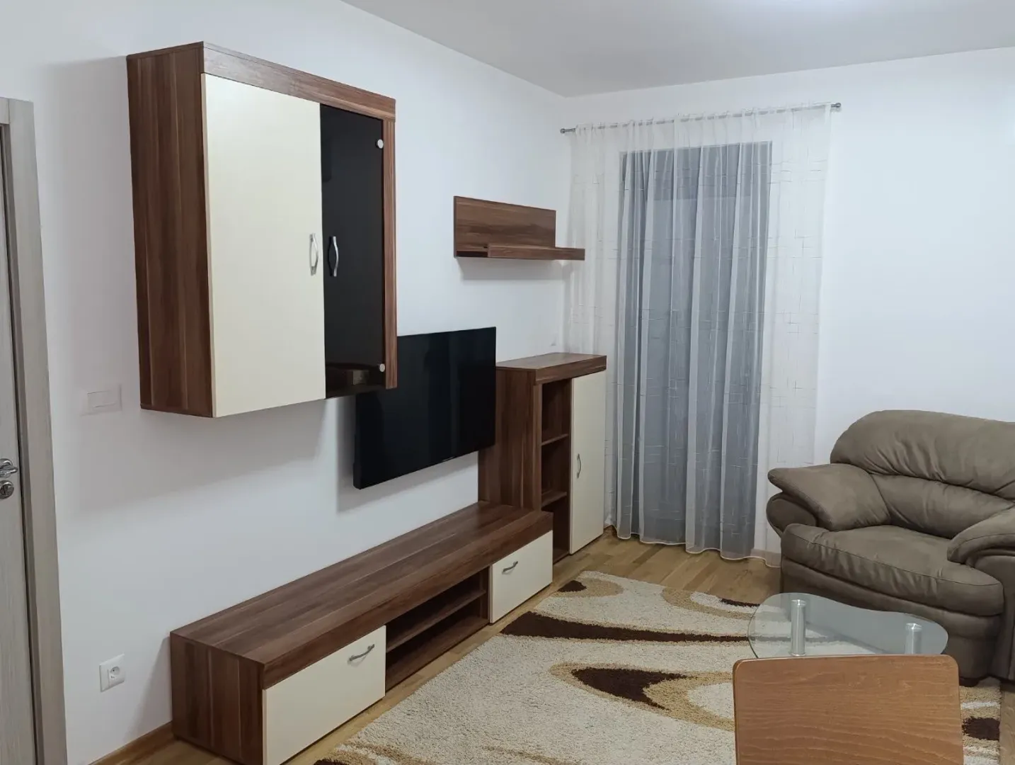 Dnevna soba sa garniturom, televizorom i drvenim namještajem.