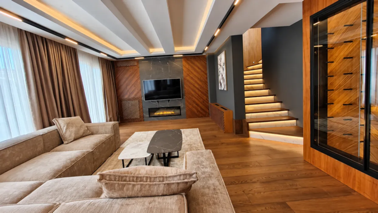 Modern living room with a sofa, built-in fireplace, TV, and stairs.