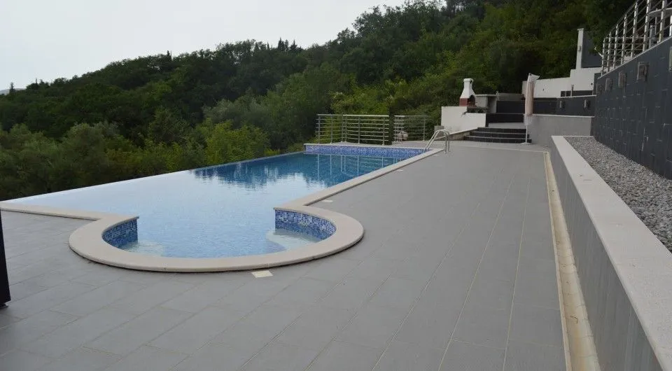 Bazen sa popločanom terasom i pogledom na šumu.