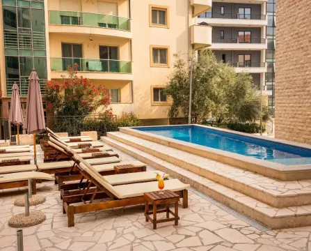 Swimming pool with sun loungers and umbrellas located in the courtyard of an apartment building. - image 6