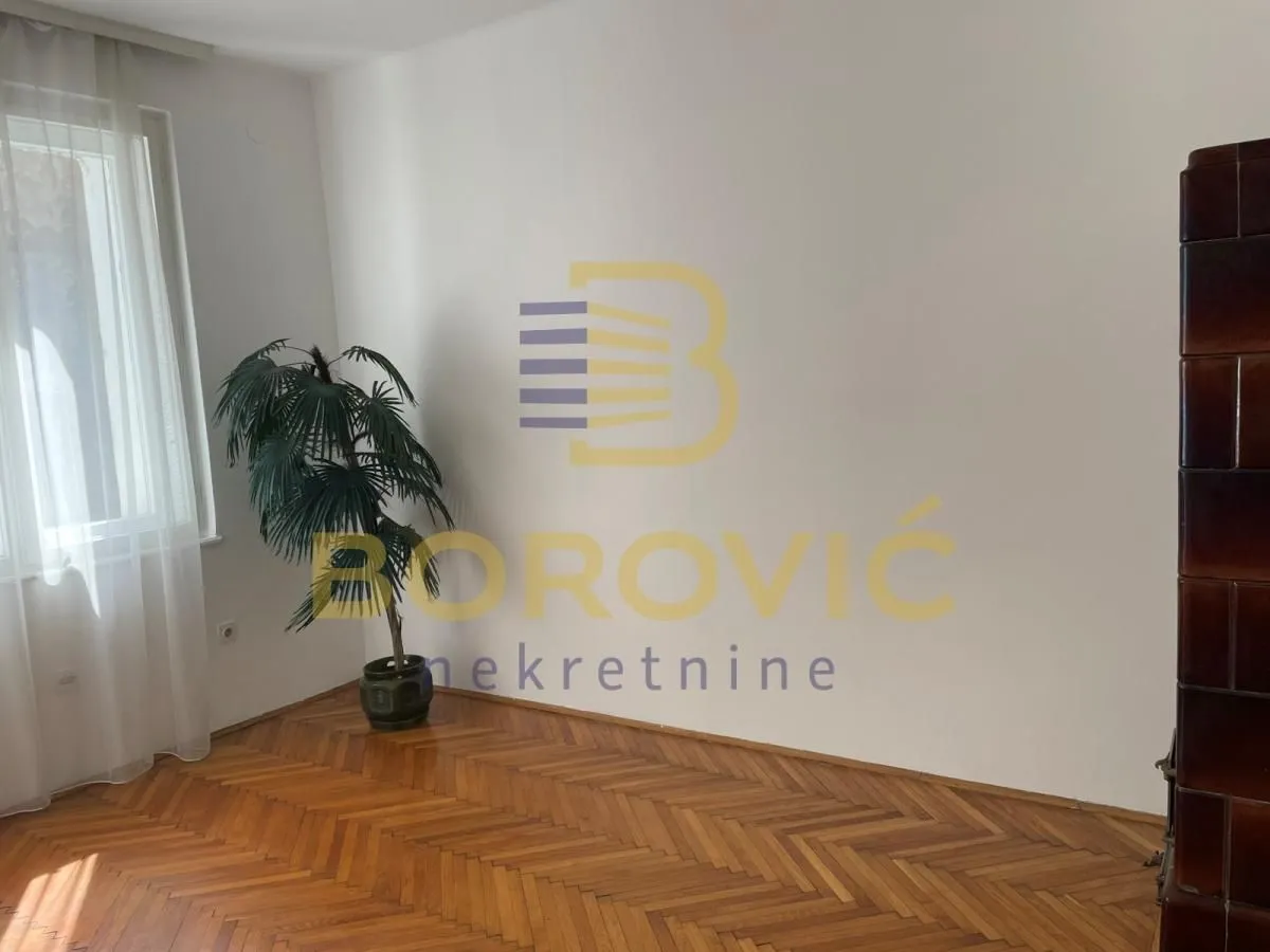 Empty room with parquet flooring and a window with white curtains.