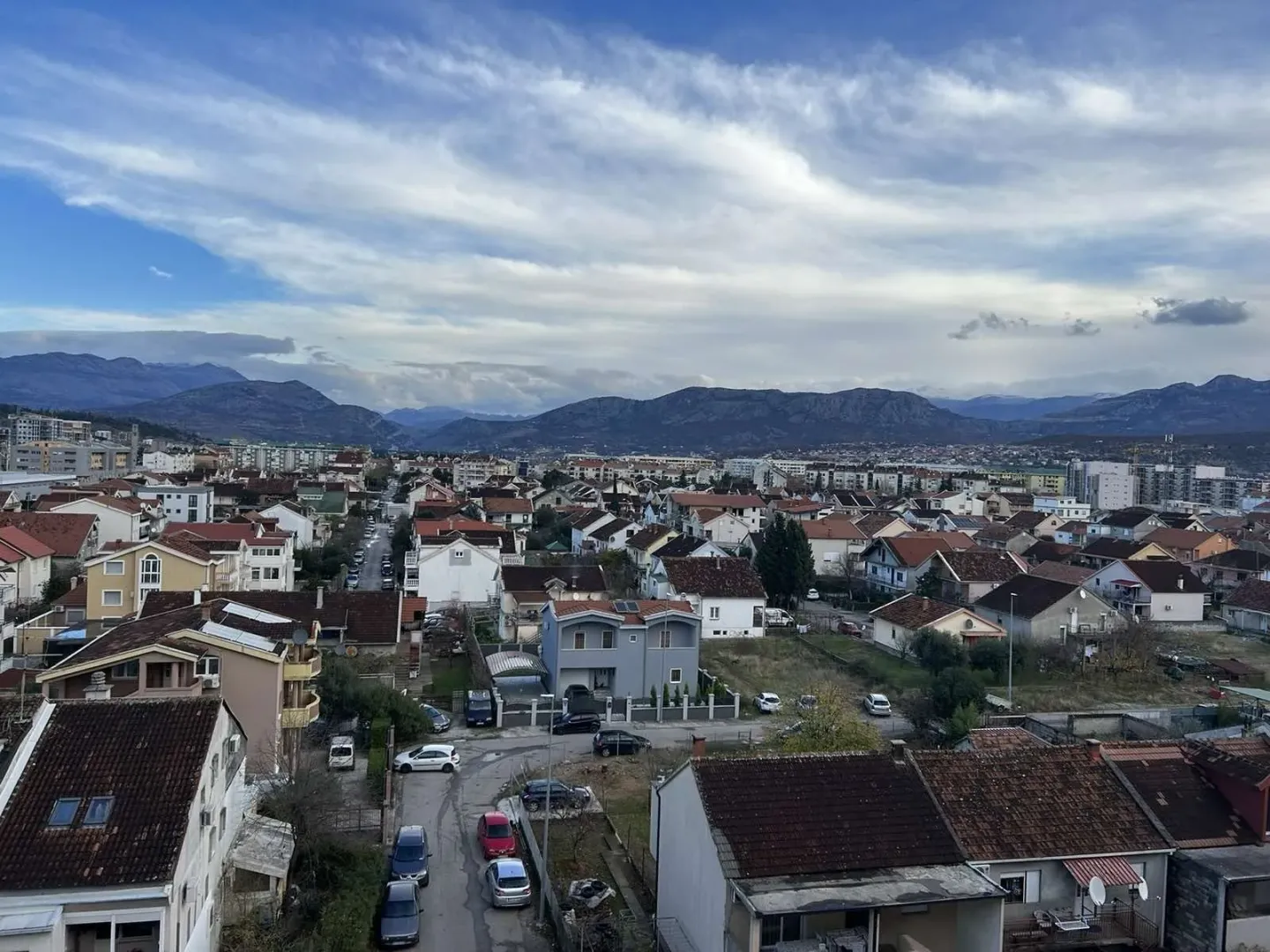 Pogled sa visine na stambeno naselje i planine u pozadini.