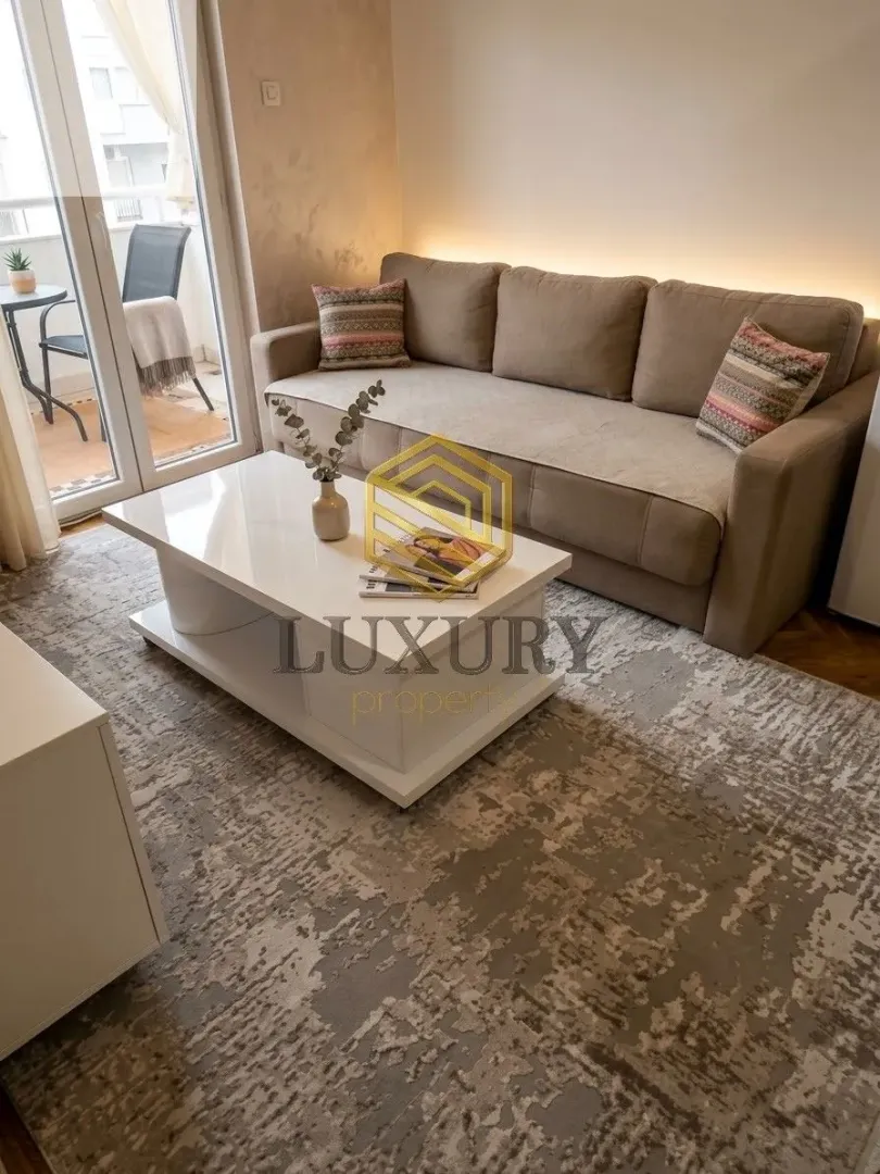 Living room with a sofa, coffee table and balcony access.