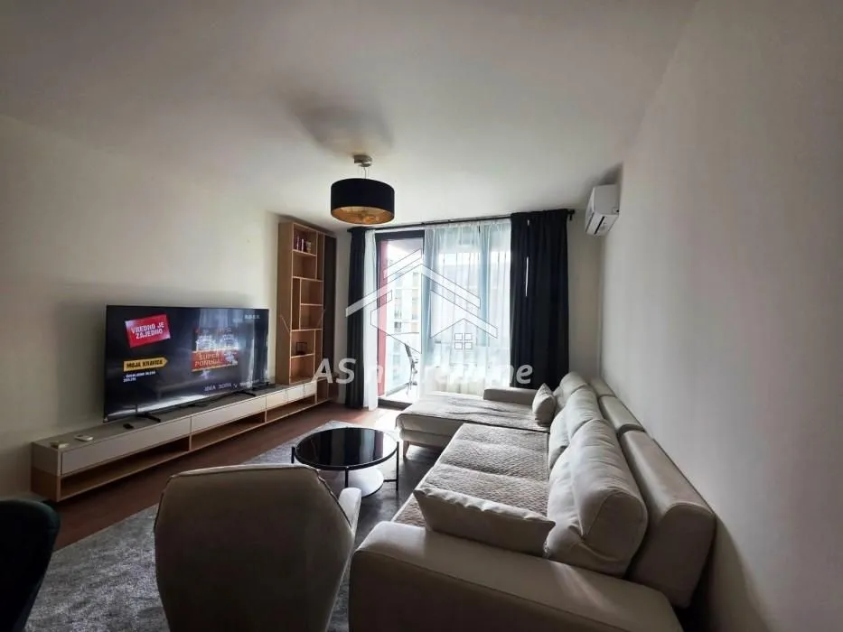 Living room with a sectional sofa, TV, and access to the terrace.