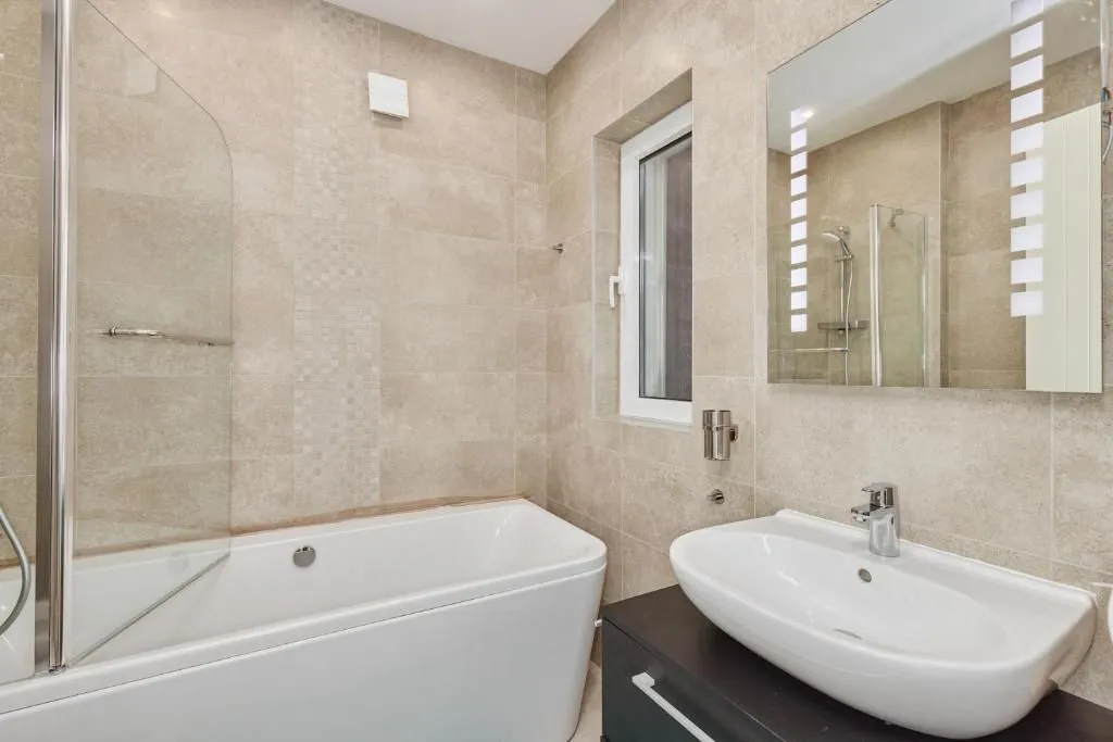 Modern bathroom equipped with a bathtub, washbasin, and mirror.