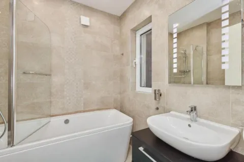 Modern bathroom equipped with a bathtub, washbasin, and mirror. - image 13