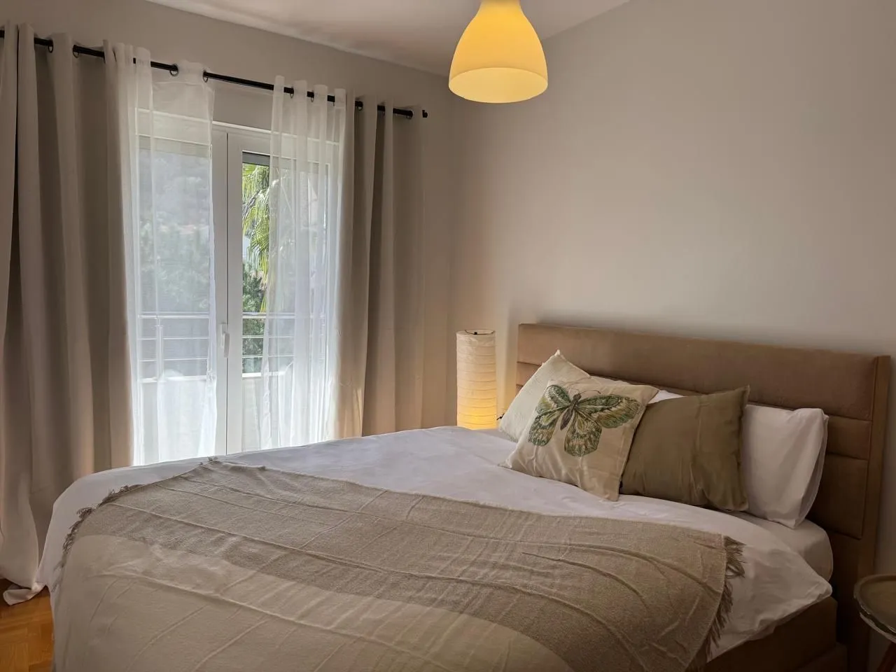 Furnished bedroom with a double bed and balcony doors.