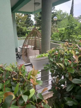 Natkrivena terasa sa visećom foteljom i zelenilom u dvorištu. - image 10