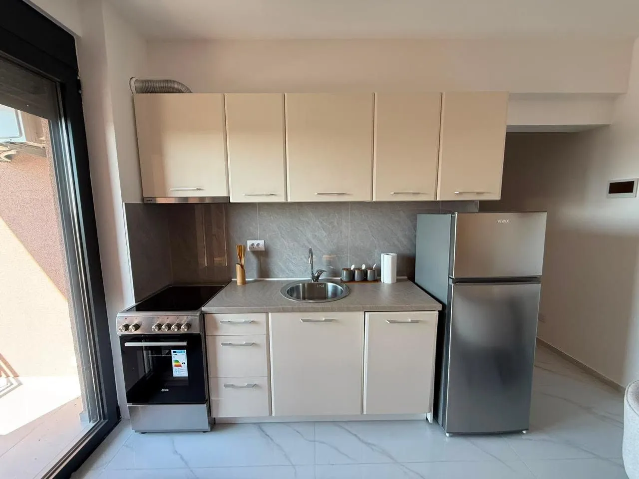 Small kitchen with light cabinetry, a stove, and a refrigerator.