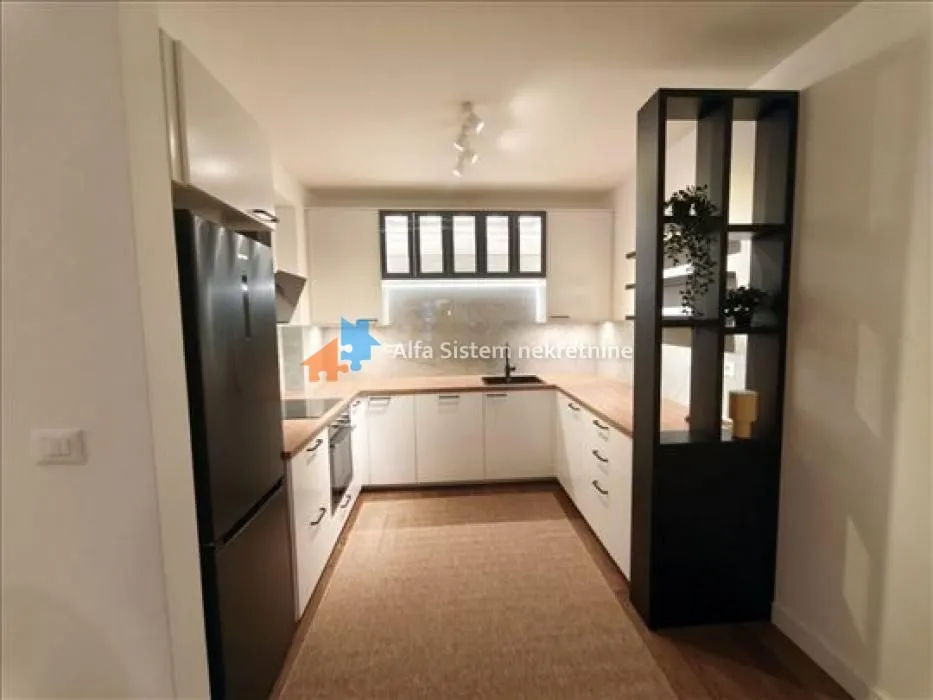 Modern U-shaped white kitchen with a black refrigerator.