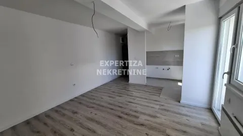 Empty room under construction with installed laminate flooring and a kitchen area. - image 2