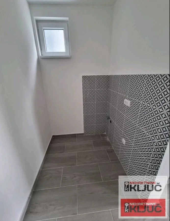 Small bathroom with tiled walls and a window.
