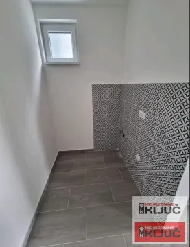 Small bathroom with tiled walls and a window. - image 7