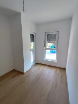 Empty bright room with white walls, wooden flooring, a window, and balcony doors. - image 9