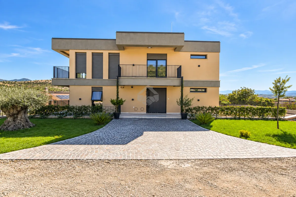 Front view of a modern two-story house with a paved driveway and landscaped lawn.