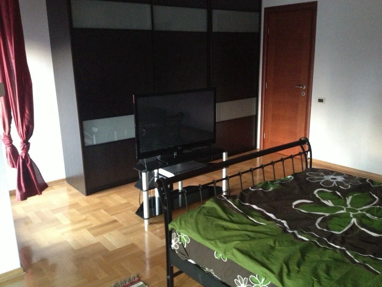 Simple bedroom with a large wardrobe and a TV.