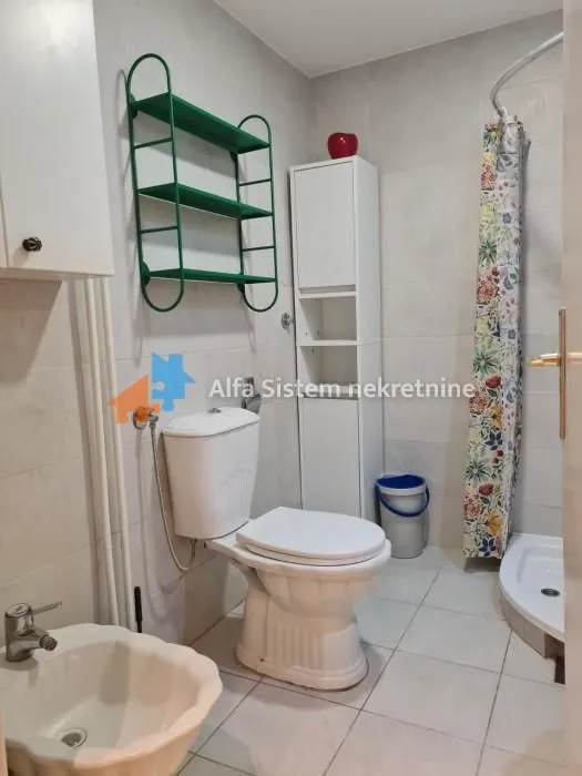 Bathroom equipped with a toilet, bidet, shower, and white bathroom furniture.