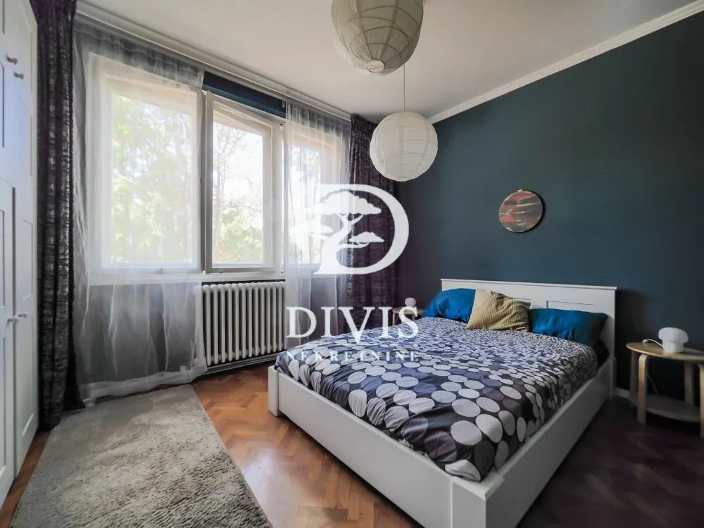Bedroom with a double bed, dark accent wall, and a large window.