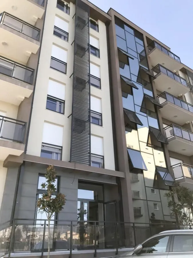 Pogled na spoljašnjost moderne stambene zgrade sa balkonom i velikim prozorima.