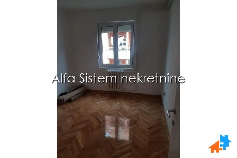 Prazna soba sa parketom i prozorom.