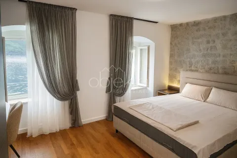 Spavaća soba sa bračnim krevetom, kamenim zidom i pogledom na more. - image 10