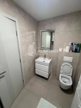Kompaktno kupatilo sa umivaonikom, ogledalom i toaletom u bež pločicama. - image 6