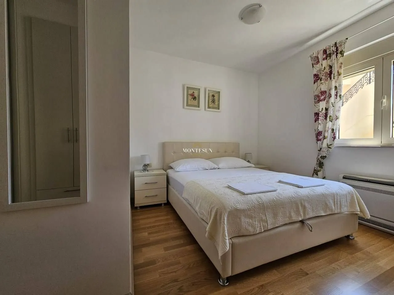 A tidy bedroom with a double bed, wardrobe, and a window.