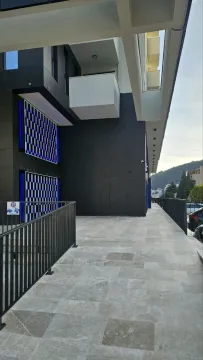 Pogled na spoljašnji dio moderne stambene zgrade sa popločanim prolazom i ogradom. - image 9