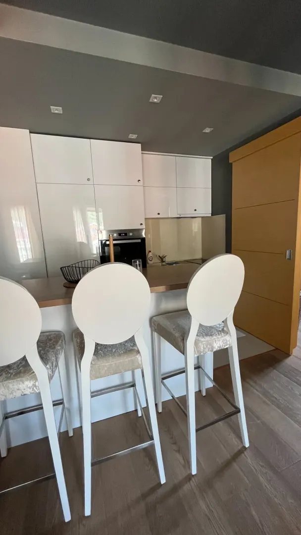 Modern kitchen with white cabinetry and a breakfast bar with bar stools.