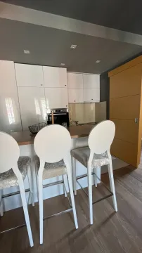Modern kitchen with white cabinetry and a breakfast bar with bar stools. - image 5