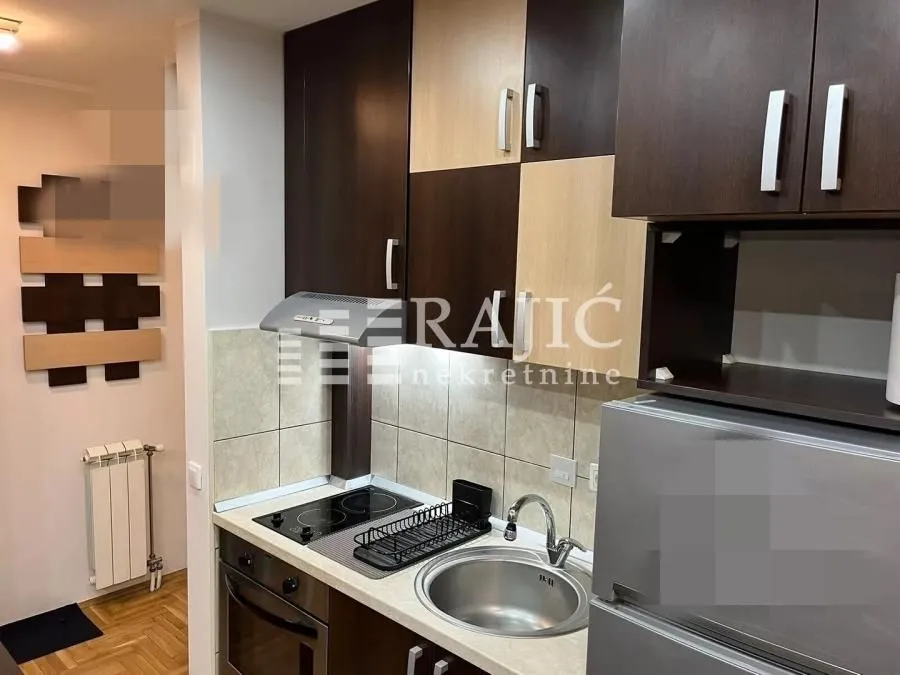 Modern kitchen with dark and light cabinets, a sink, and a built-in cooktop.