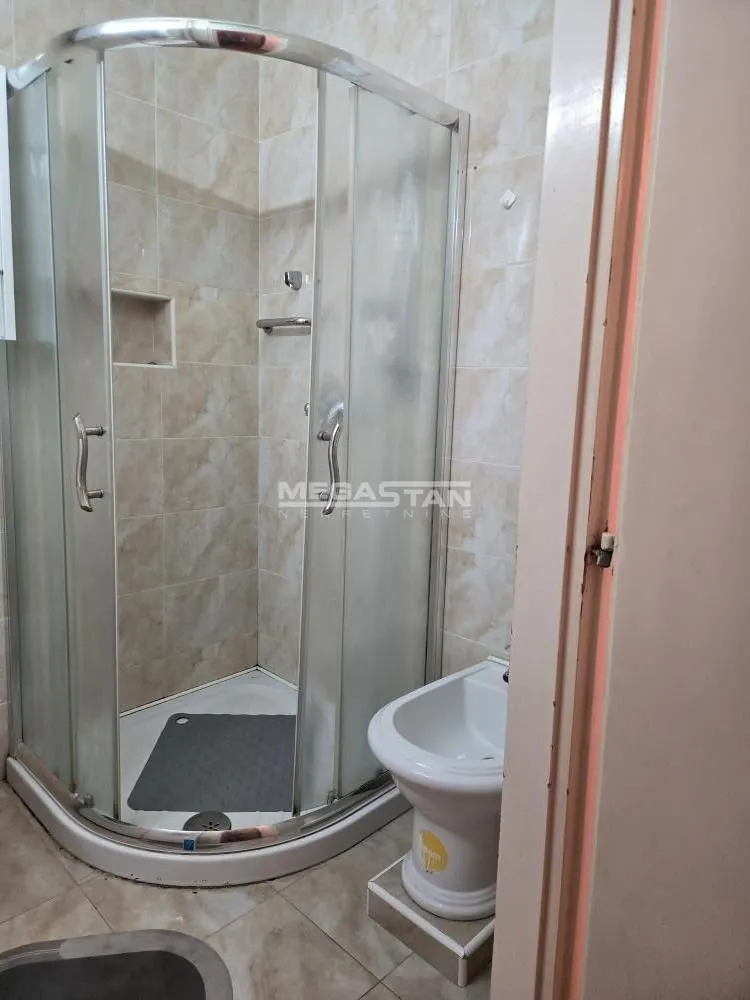 Kupatilo sa tuš kabinom i sanitarijama obloženo pločicama.